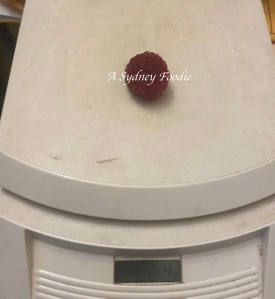 a single raspberry weighing 4g on a kitchen scale